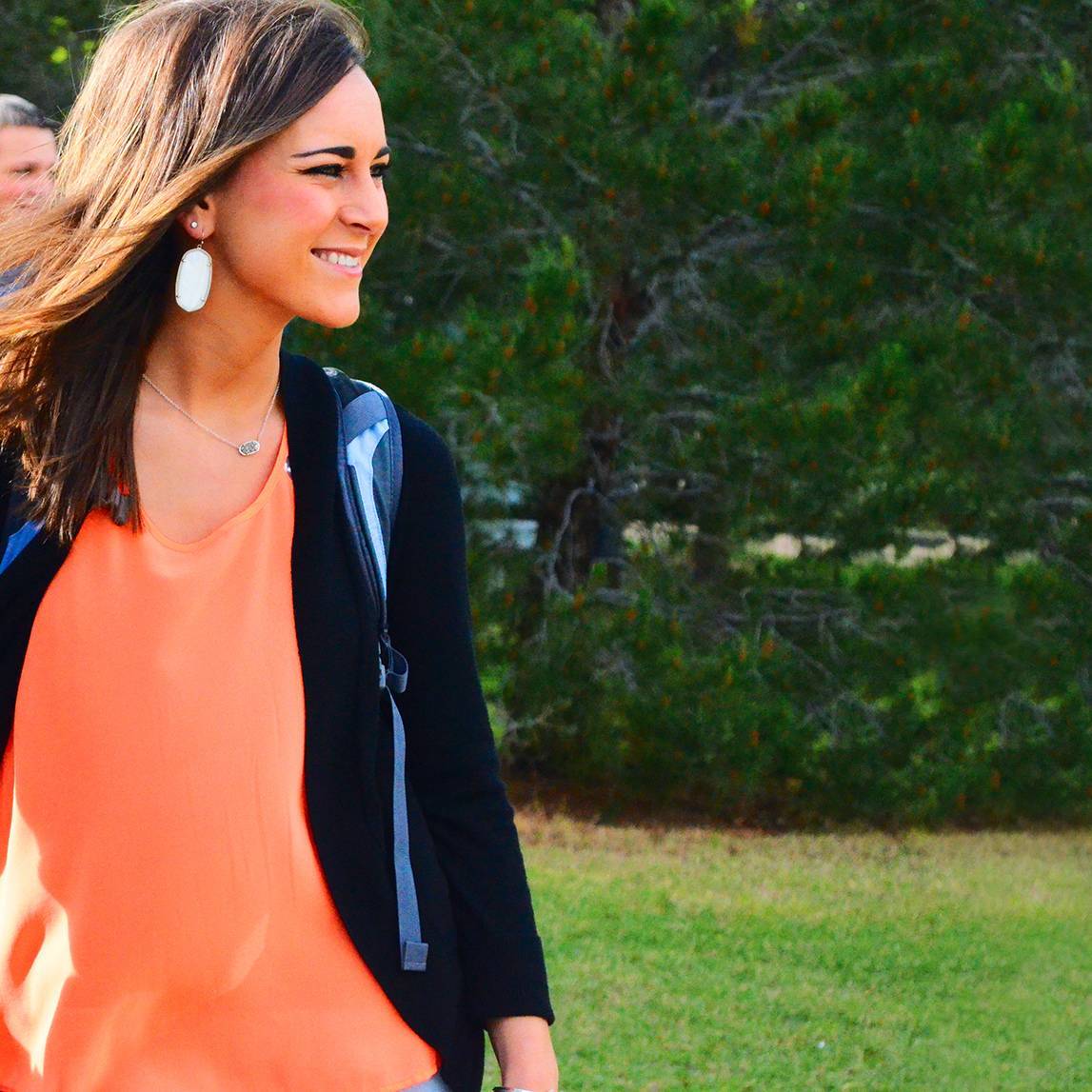 A woman walking on campus with a backpack